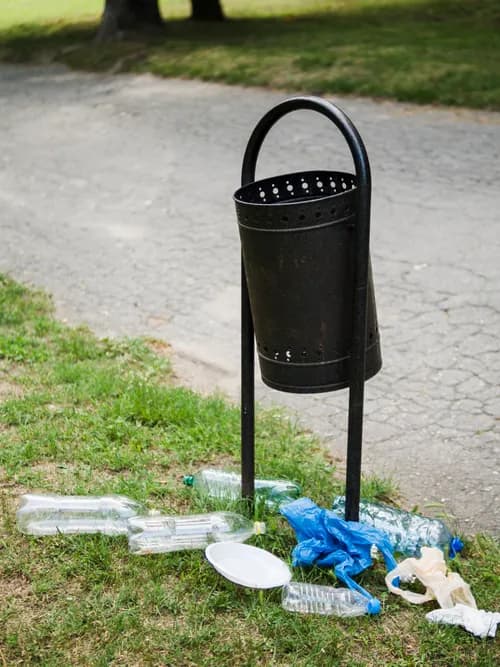 Plastic garbage near a metallic bin in a park